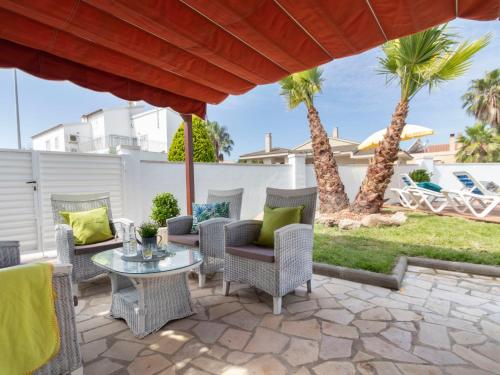 a patio with chairs and a table and palm trees at Holiday Home Estrella by Interhome in Riumar