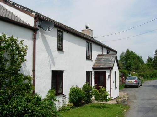 una casa bianca con una macchina parcheggiata di fronte di The Old School House Bed and Breakfast a Llanbrynmair