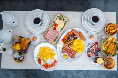 a table with plates of breakfast food and cups of coffee at Hotel Bacchus in Livno