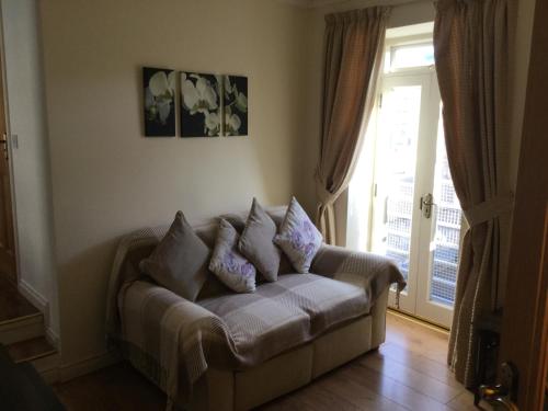 a couch with pillows in a living room with a window at Coach house in Armagh