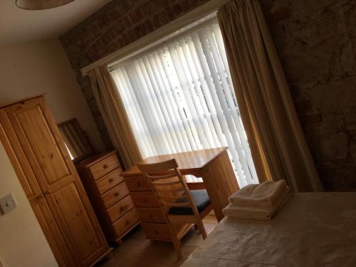 a bedroom with a window with a table and a chair at Coach house in Armagh