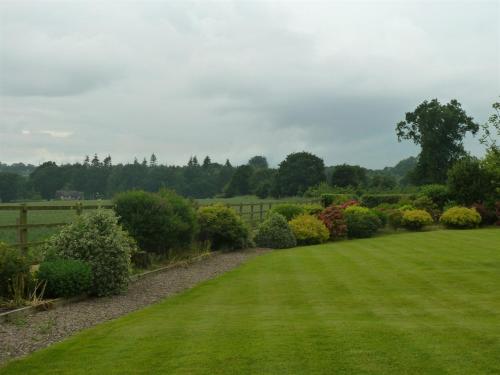 ogród z zieloną trawą i krzakami oraz ogrodzeniem w obiekcie The Coach House w mieście Milford