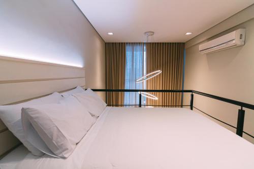 una camera da letto con un letto con cuscini bianchi e una finestra di Multihouse - Moderno Duplex Berrini - WTC - Brooklin a San Paolo