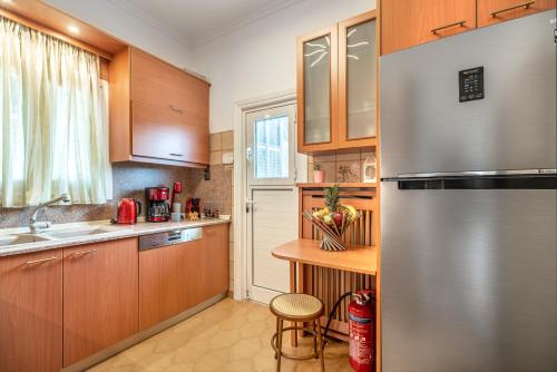 a kitchen with wooden cabinets and a stainless steel refrigerator at Villa Artemida Vravrona in Vravrona