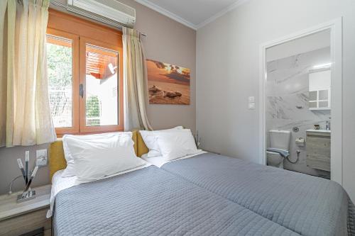 a bedroom with a bed with white sheets and a window at Villa Artemida Vravrona in Vravrona
