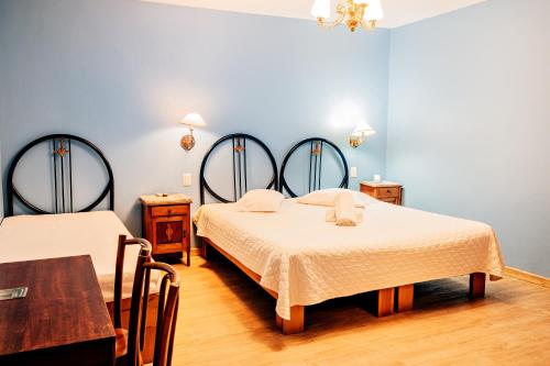 a bedroom with two beds and a table in it at Pousada Casa Rosa in Canela