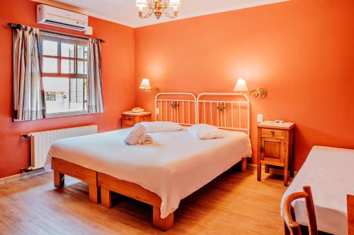 a bedroom with orange walls and a bed and a window at Pousada Casa Rosa in Canela