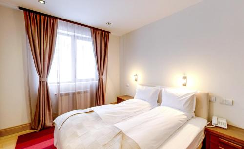 a bedroom with a large white bed and a window at The Lodge Hotel in Borovets