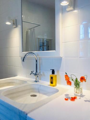 a bathroom with a sink with a mirror and orange flowers at El Molino Estepona in Estepona