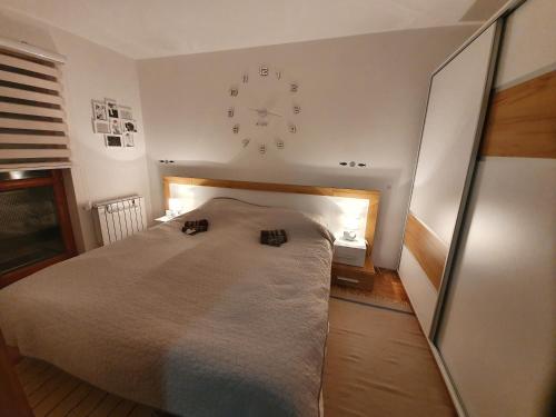 Un dormitorio con una cama y un reloj en la pared. en Apartman Lari, en Vlašić