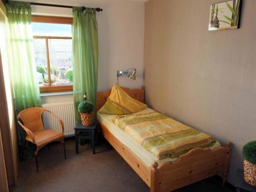 a bedroom with a bed and a chair and a window at Ferienwohnung Stirnbergblick in Ehrenberg