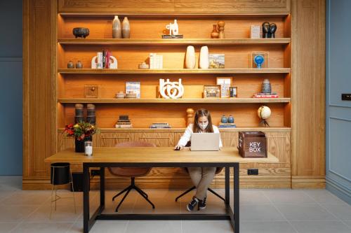 a woman sitting at a table with a laptop at Mercure Porto Centro Aliados in Porto
