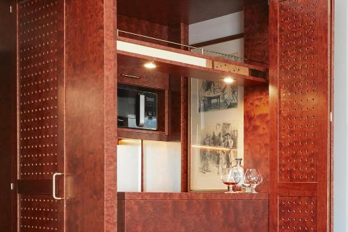 a cabinet with two wine glasses and a mirror at Living Hotel De Medici in Düsseldorf