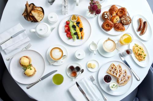 a white table with plates of breakfast foods and drinks at One Aldwych in London