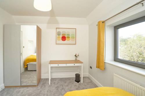 1 dormitorio con cama, escritorio y ventana en Home from home - 4 Double Bed House with Parking en Slough
