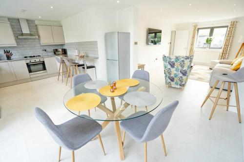 a kitchen with a glass table and blue chairs at Home from home - 4 Double Bed House with Parking in Slough