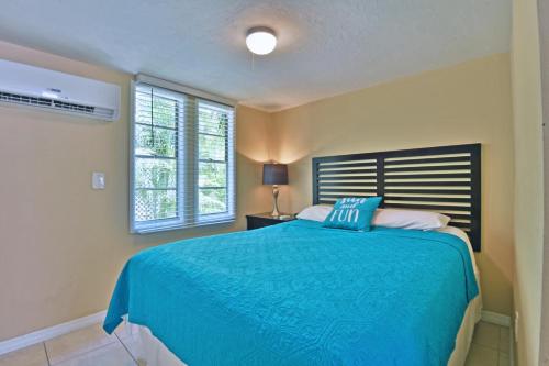 a bedroom with a blue bed and two windows at Siesta Key Beach - Bari 665 #2 in Siesta Key