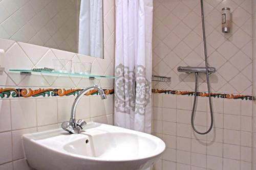 a bathroom with a shower, sink, and tub at Hôtel de l'Amphithéâtre in Arles
