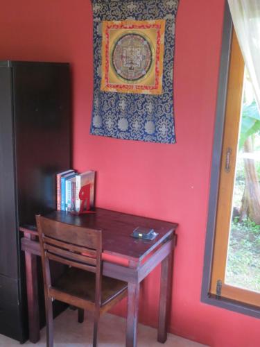 a wooden table with a chair next to a red wall at Manora Garden in Phangnga