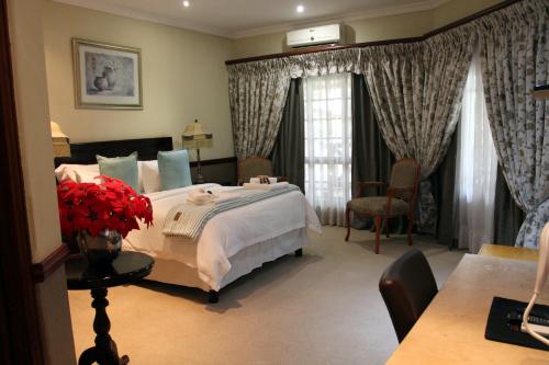a bedroom with a large bed and a table and chairs at Prinshof Manor Guesthouse in Pretoria