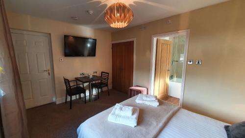 a bedroom with two beds and a table and a television at The Gower Hotel in Swansea