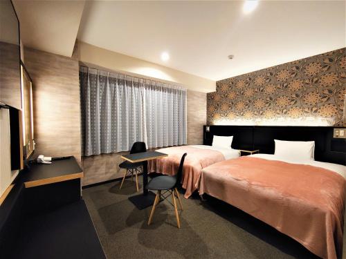 ein Hotelzimmer mit 2 Betten und einem Schreibtisch in der Unterkunft Green Rich Hotel Kyoto Station South (Artificial hot spring Futamata Yunohana) in Kyoto