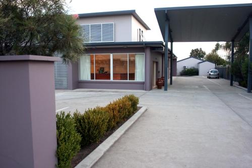 a house with a sidewalk in front of a building at Mackellar Motel in Gunnedah
