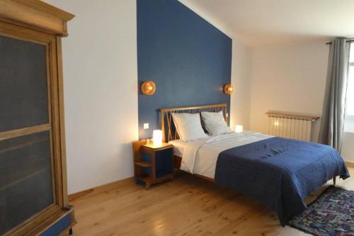 a bedroom with a bed with a blue wall at Belle longère au calme - L'auguste maison d'hôtes in Valensole
