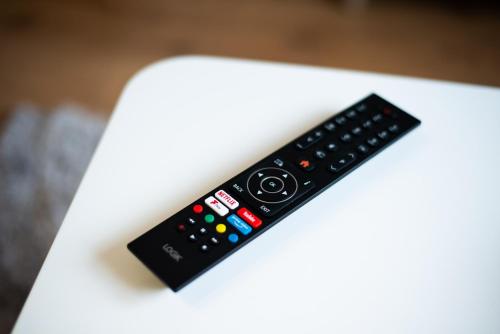 a remote control sitting on top of a white table at Private Parking, Garden, Close to Beach! in Swansea