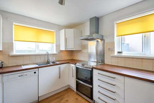 a kitchen with white cabinets and two windows at Private Parking, Garden, Close to Beach! in Swansea