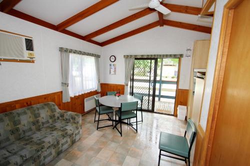 sala de estar con sofá, mesa y sillas en Wangaratta Caravan Park, en Wangaratta