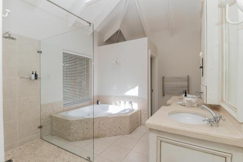 a bathroom with a tub and a sink and a shower at Fernwood Manor Boutique Guest House in Cape Town