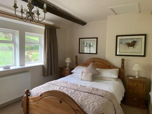 a bedroom with a large bed and two windows at Royds Hall Cottage in Keighley