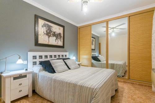 a bedroom with a white bed and a mirror at New and modern apartment in Salinetas beach. in Salinetas