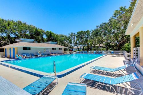 a swimming pool with blue lounge chairs next to a building at Buddy's Place at the Beach in New Smyrna Beach