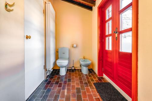 a bathroom with a toilet and a red door at Villa Gallus - Jelsa, Hvar in Jelsa