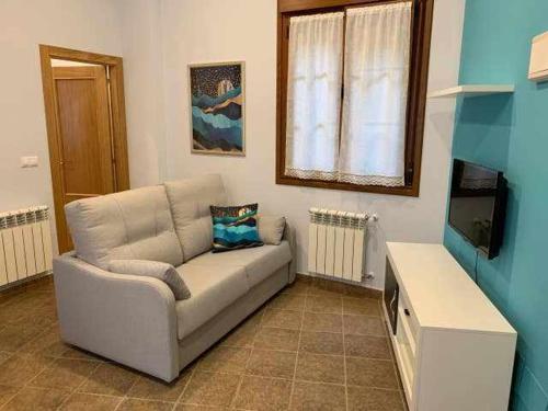 ein Wohnzimmer mit einem Sofa und einem TV in der Unterkunft Cumbres de los Picos Apartamento Buhos in Poo de Cabrales