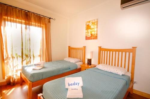 2 camas individuales en una habitación con ventana en Apartamento Corcovada - By Bedzy, en Albufeira
