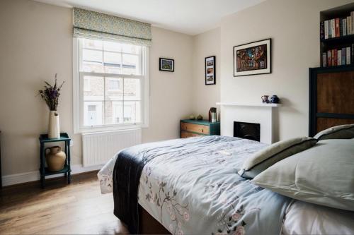 a bedroom with a bed and a fireplace and a window at 107 Nunnery Lane - a House of York holiday home in York
