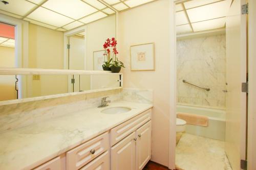 a bathroom with a sink and a toilet and a mirror at Whaler #763 Condo in Lahaina