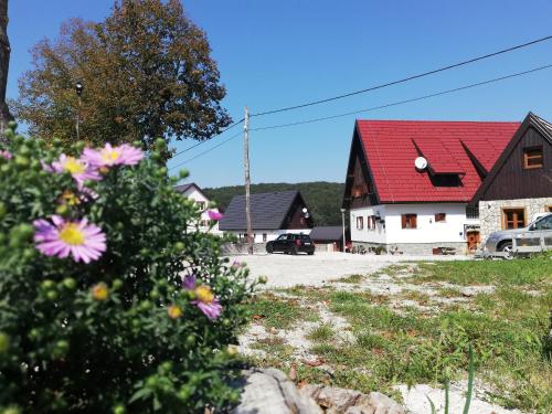 a house with a red roof and some flowers at Rustic Lodge Plitvice in Plitvička Jezera