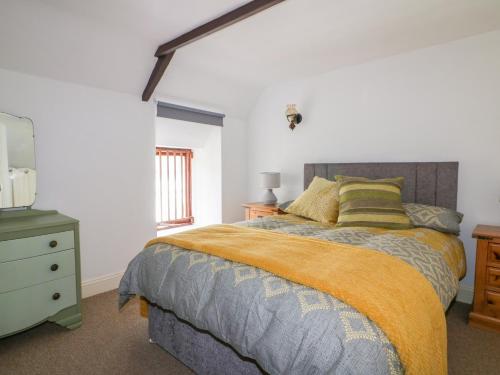a bedroom with a bed and a dresser and a window at The Old Coach House in St Austell