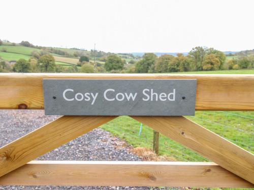 a sign on a fence that reads cosy cow shed at The Cosy Cowshed in Axminster