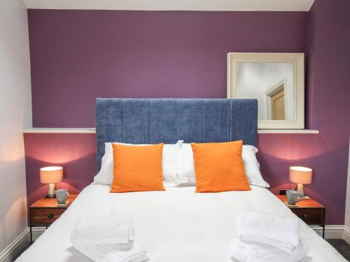 a bedroom with a bed with a blue headboard and orange pillows at The Cosy Cowshed in Axminster