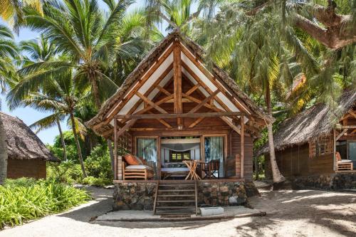 a cabin on the beach with palm trees at Constance Tsarabanjina - All Inclusive in Nosy Mitsio