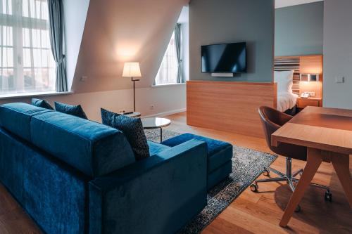 a living room with a blue couch and a bedroom at The Wellem, in The Unbound Collection by Hyatt in Düsseldorf