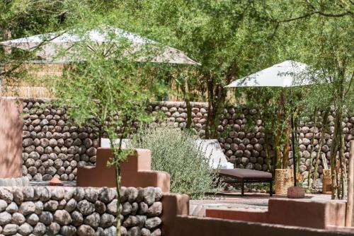 a garden with a bench and an umbrella at Naturalis Hotel in San Pedro de Atacama
