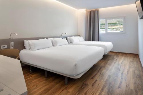 un grande letto bianco in una stanza con finestra di B&B HOTEL Almería Vicar a Aguadulce