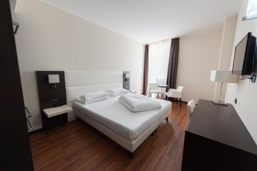 1 dormitorio con cama, escritorio y ventana en Kona Hotel Verona en Negrar