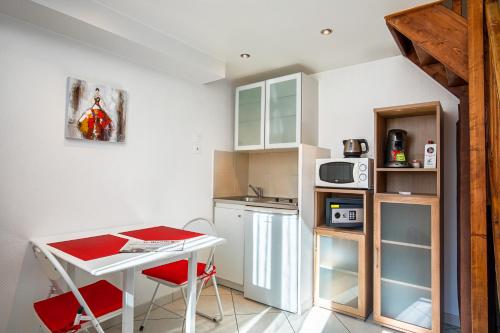 a small kitchen with a white table and red chairs at Hotel De L'Horloge in Paris